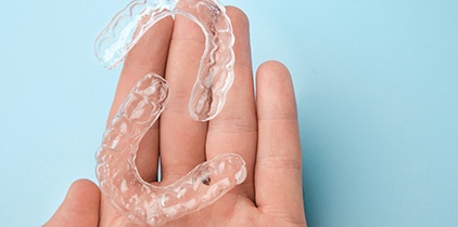 Patient holding clear aligners in palm of their hand
