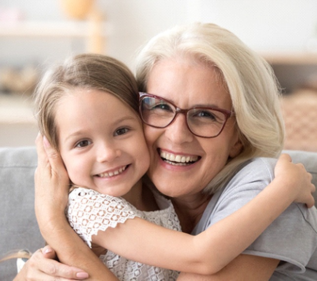 Older woman with dentures hugging young child