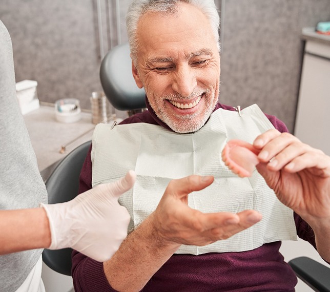 A dentist showing dentures to an older patient