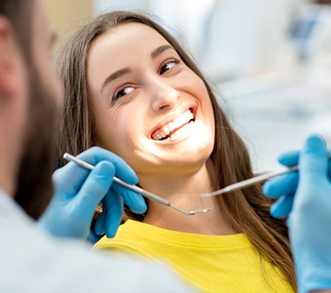 A female patient smiles while her dentist in Edmond prepares to look at her teeth and gums in Edmond