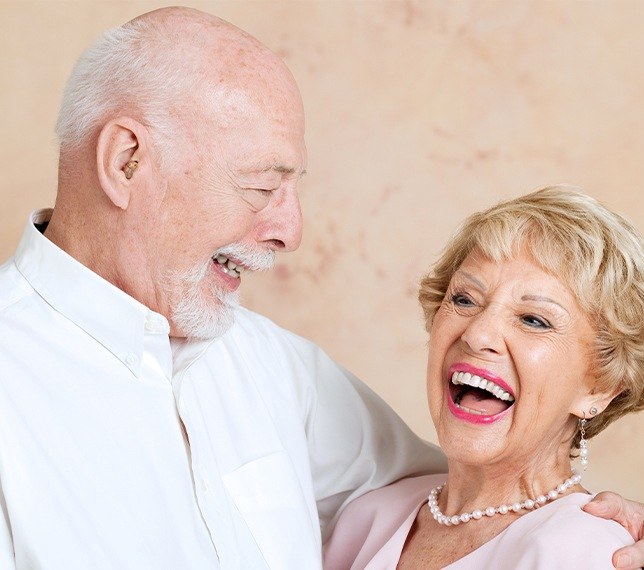 Man and woman smiling after denture placement