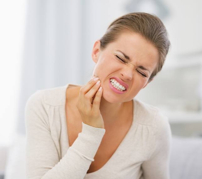 Woman in need of  root canal therapy holding jaw in pain