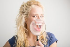 Woman with smiling with magnifying glass on her teeth