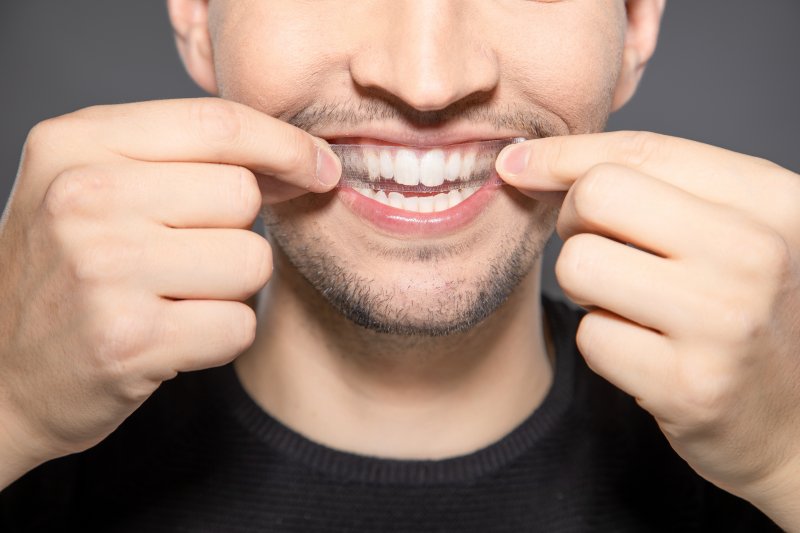 Man applying a whitening strip to his teeth