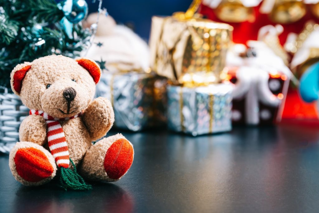 Holiday bear next to piles of presents for toy drive